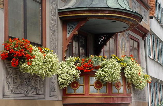 Разноцветные цветы на полукруглом балконе и окне
