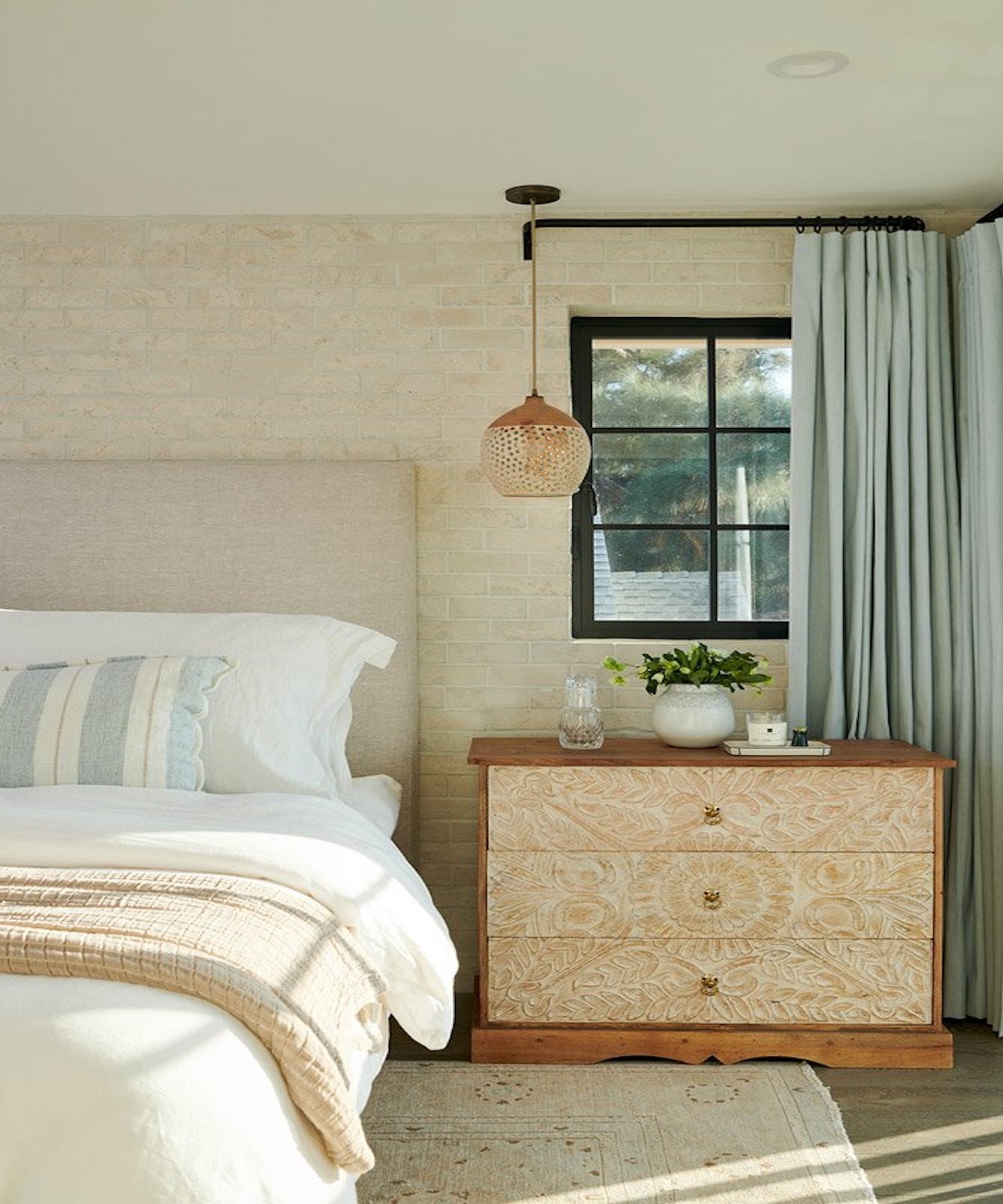 Спальня с деревянным комодом и светлым интерьером