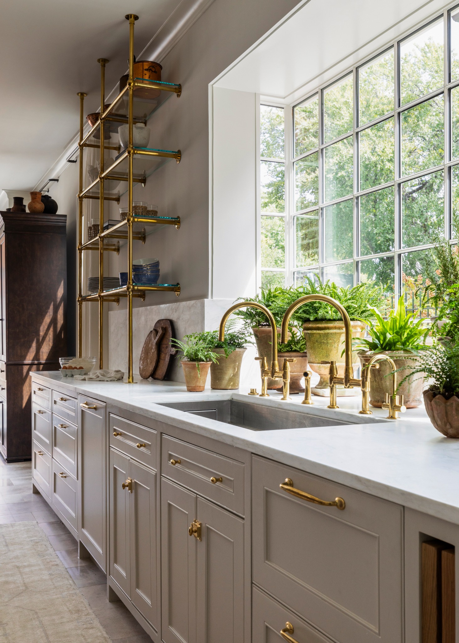 Светлая кухня с золотыми смесителями и растениями