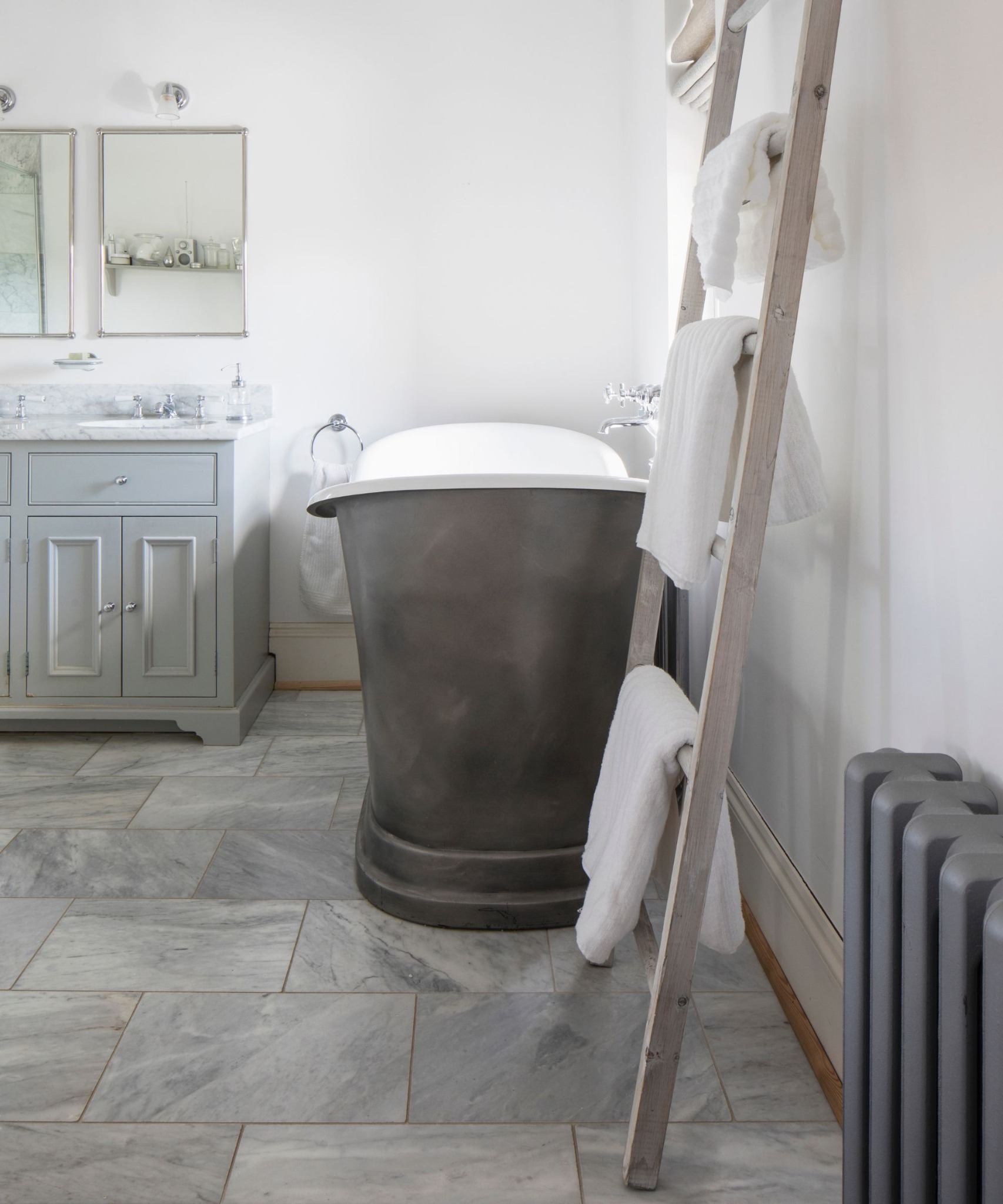 Светлая ванная с чугунной ванной и лестницей для полотенец