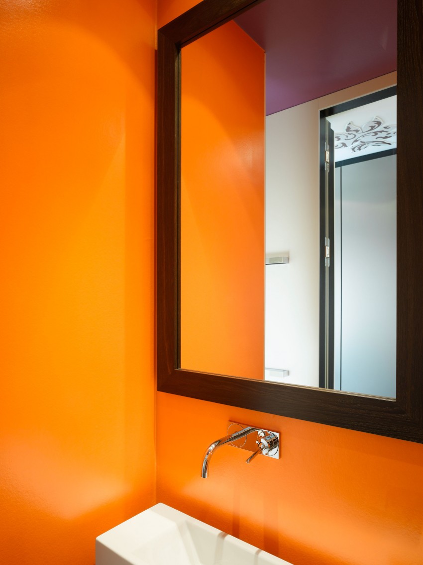 Большое зеркало в коричневой раме на оранжевой стене санузла