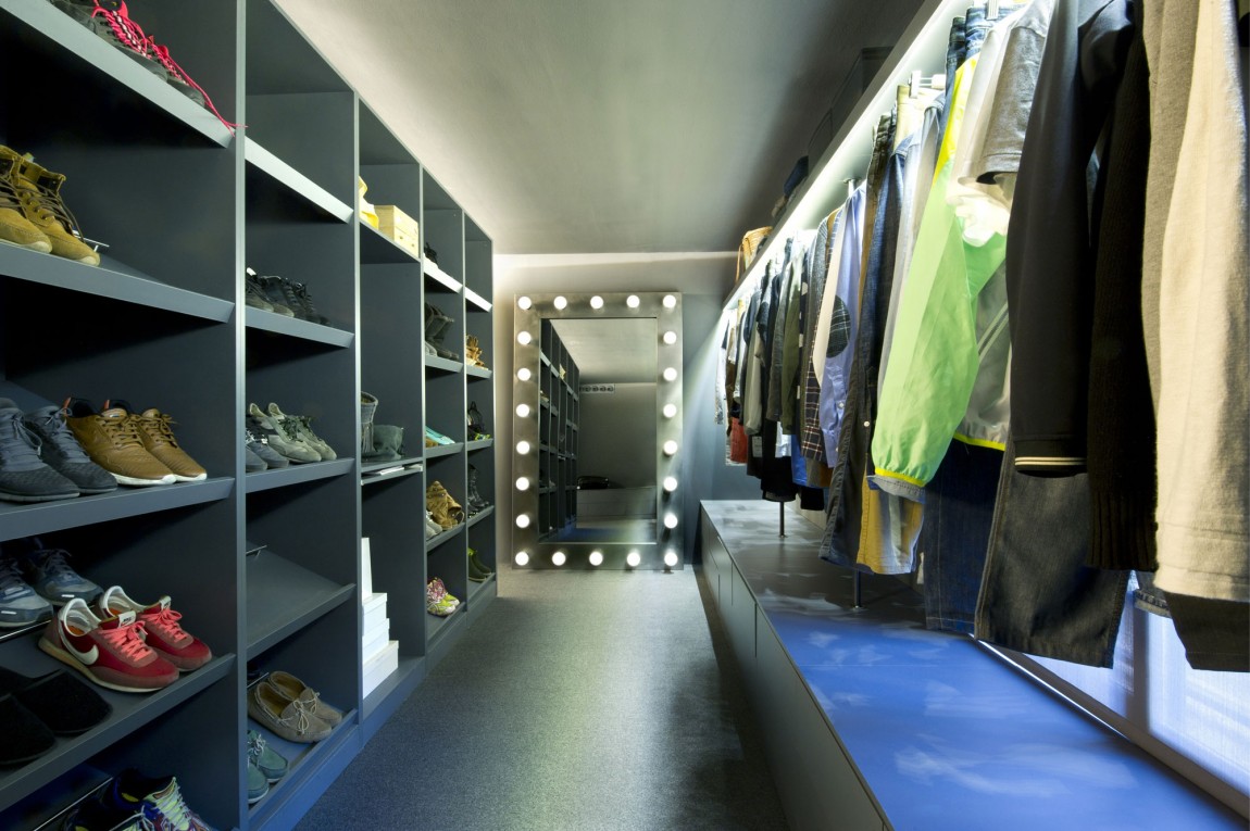 Шкаф без дверей расположен полностью на всю длину гардеробной в лофт-апартаментах