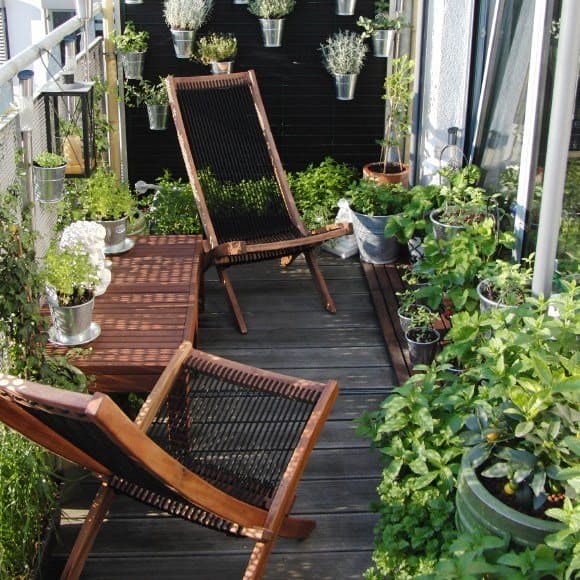 Декор маленького балкона: плетеные кресла в окружении густой зелени