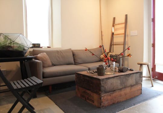 Деревенский стиль в интерьере: мягкая обивка дивана и старинный столик из дерева