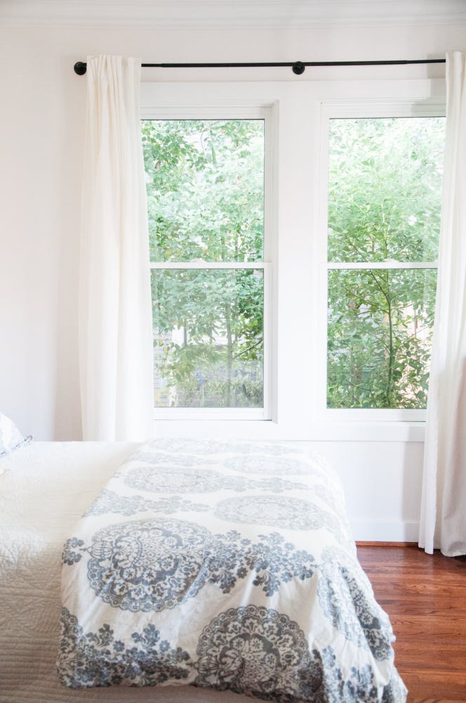 Элегантный интерьер белой спальни с большим окном