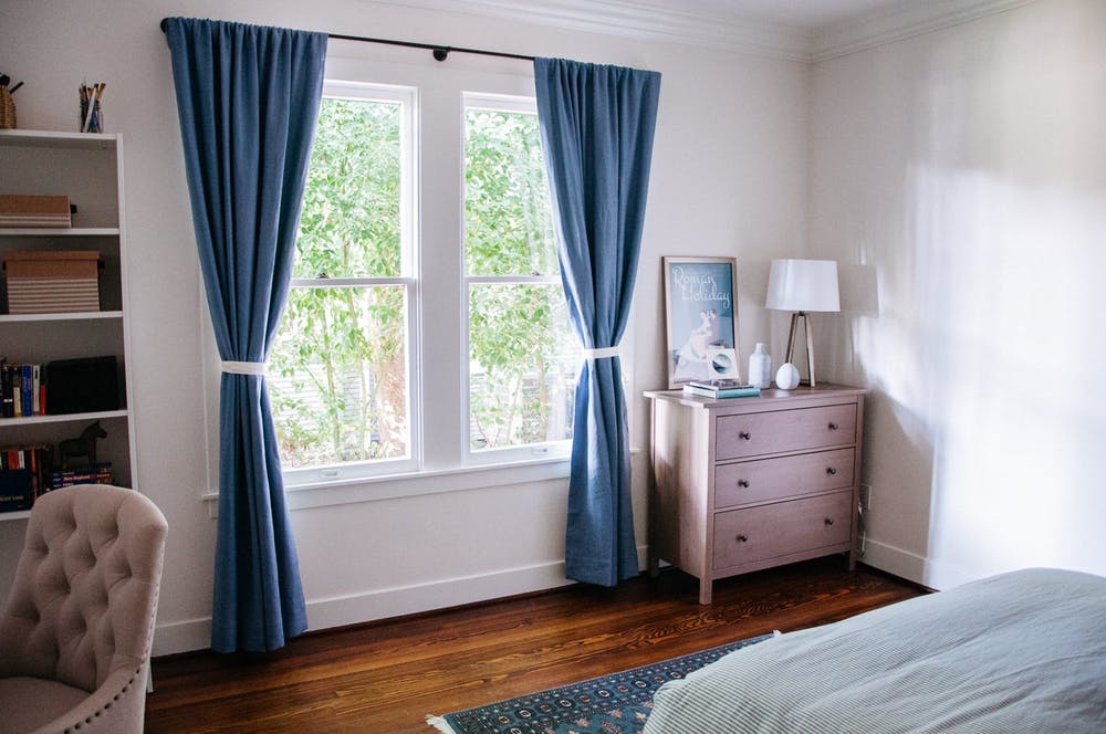 Синие шторы и коврик как яркие элементы декора в элегантном интерьере белой спальни