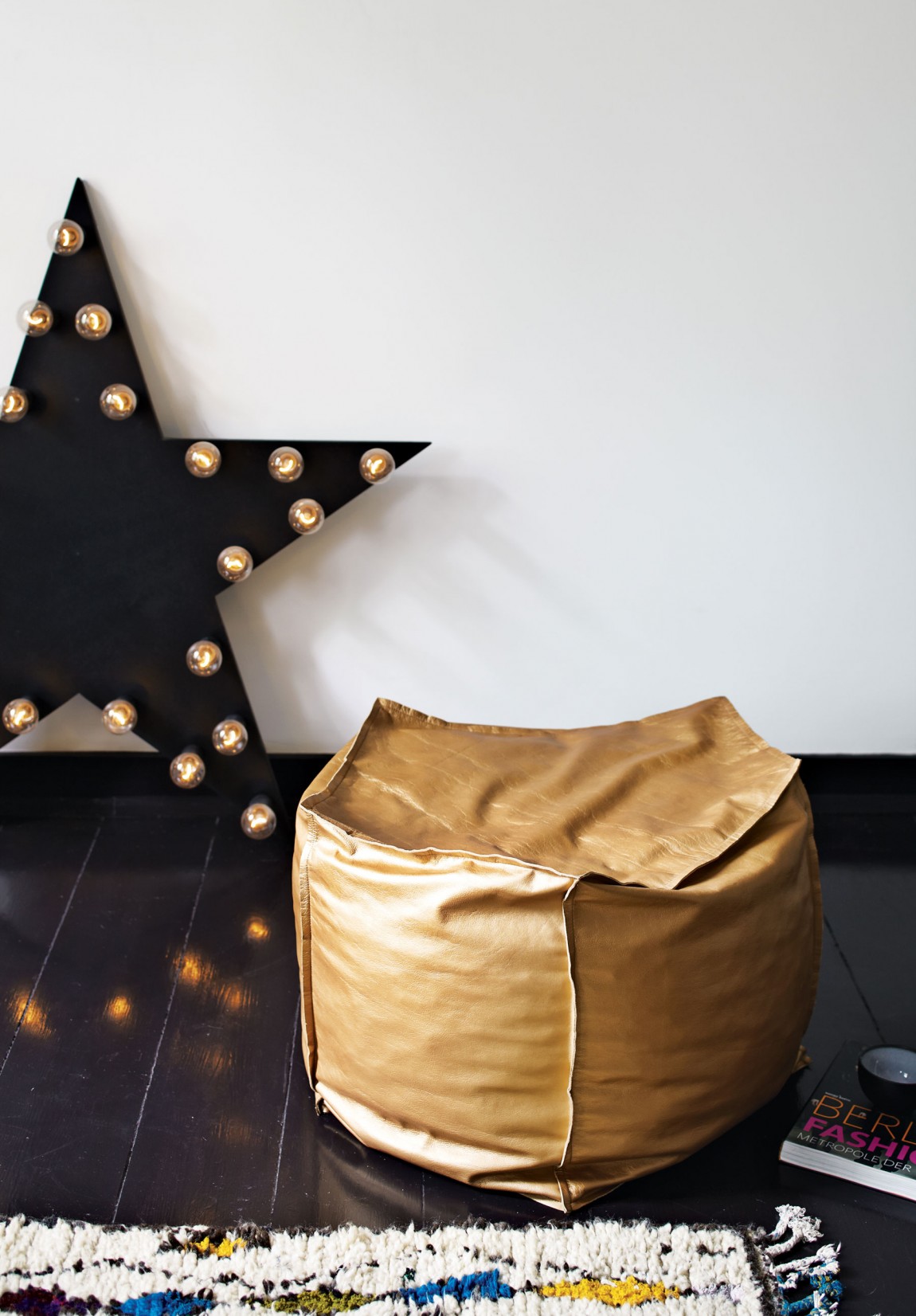 Стильные аксессуары: мягкий пуф золотистого цвета и напольный светильник в форме звезды