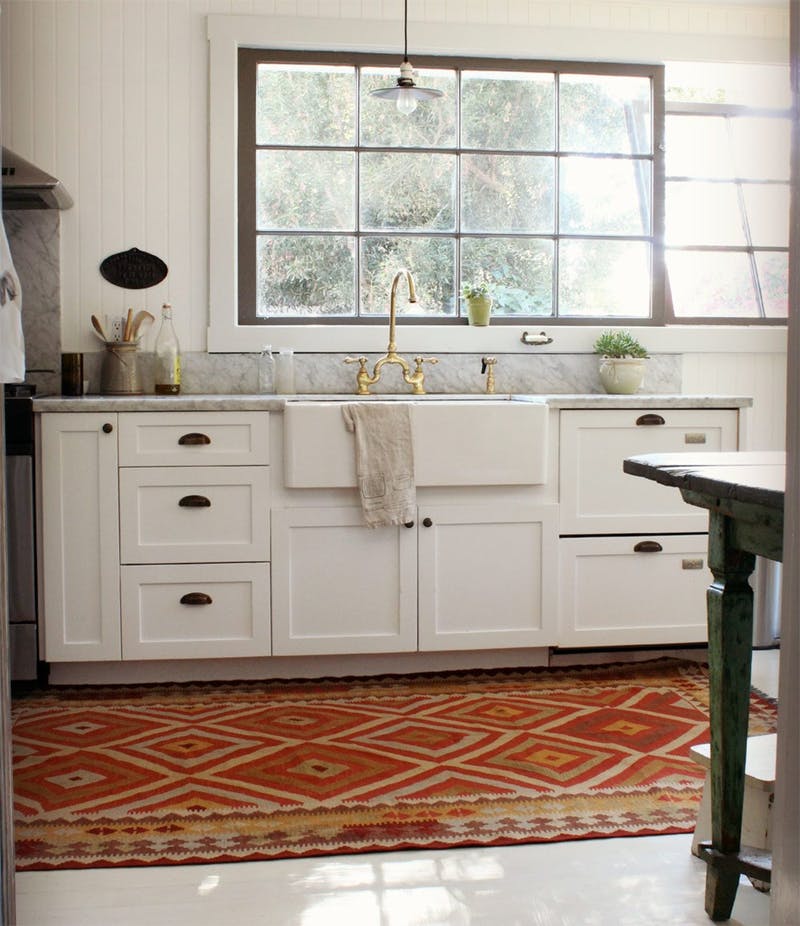 Яркий ковер с орнаментом в деревенском стиле в дизайне интерьера белой кухни