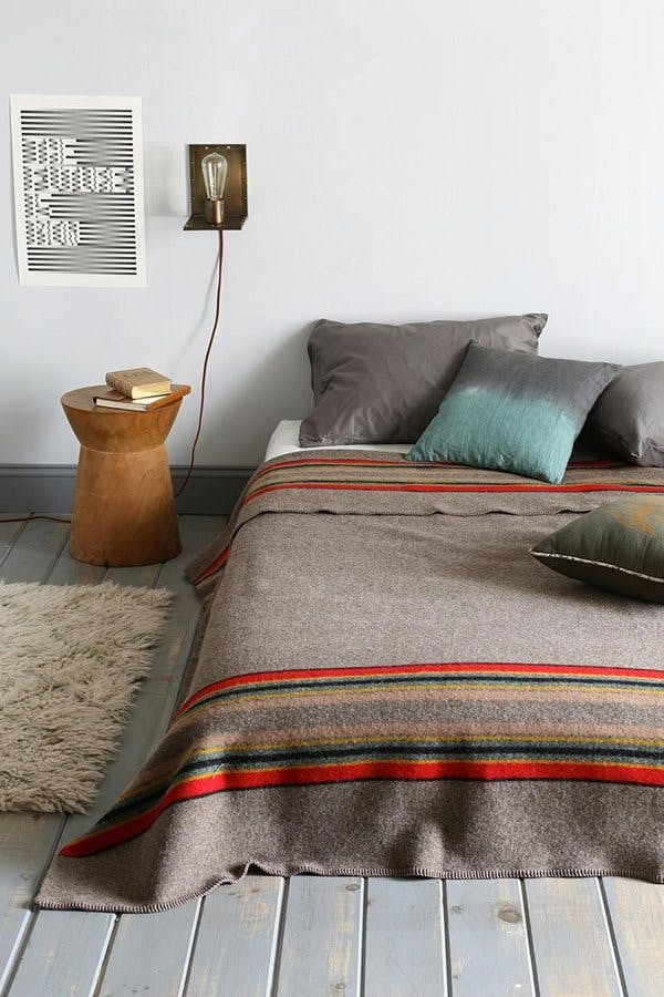 Яркий текстиль в промышленном дизайне интерьера светлой спальни