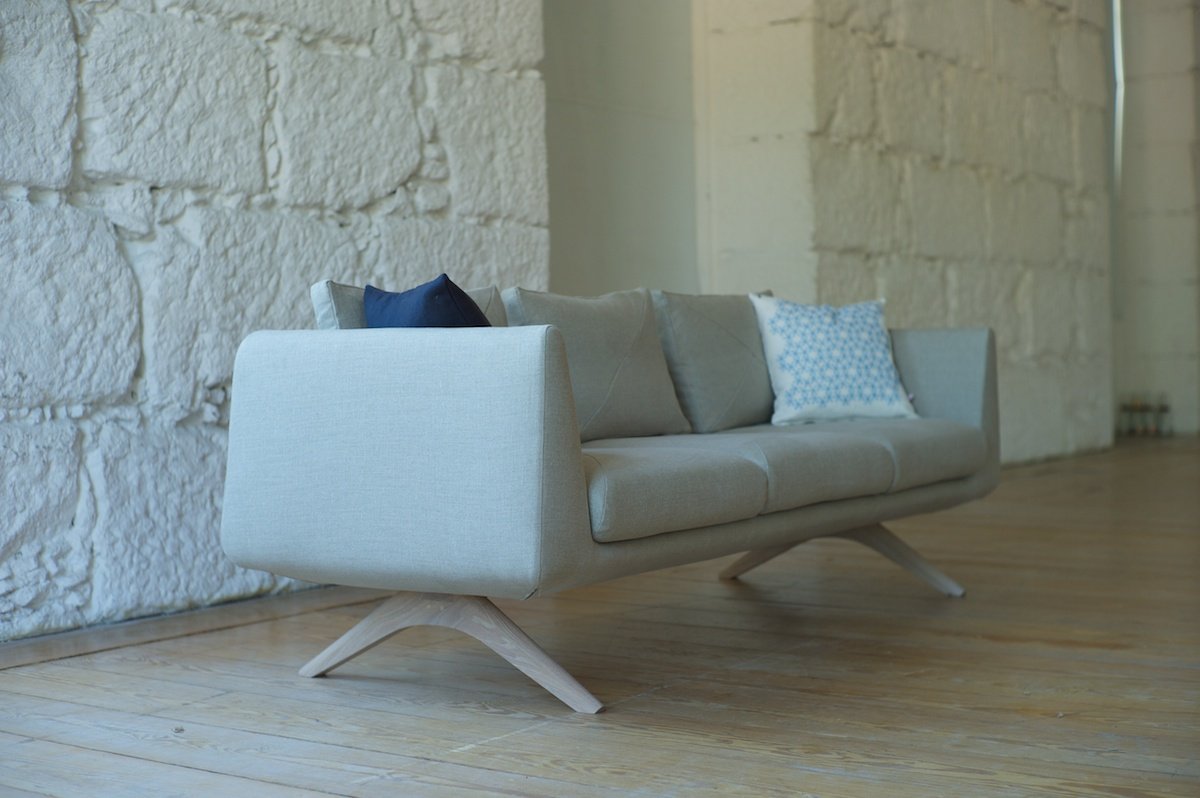 Современная модель белого дивана с изящными деревянными ножками